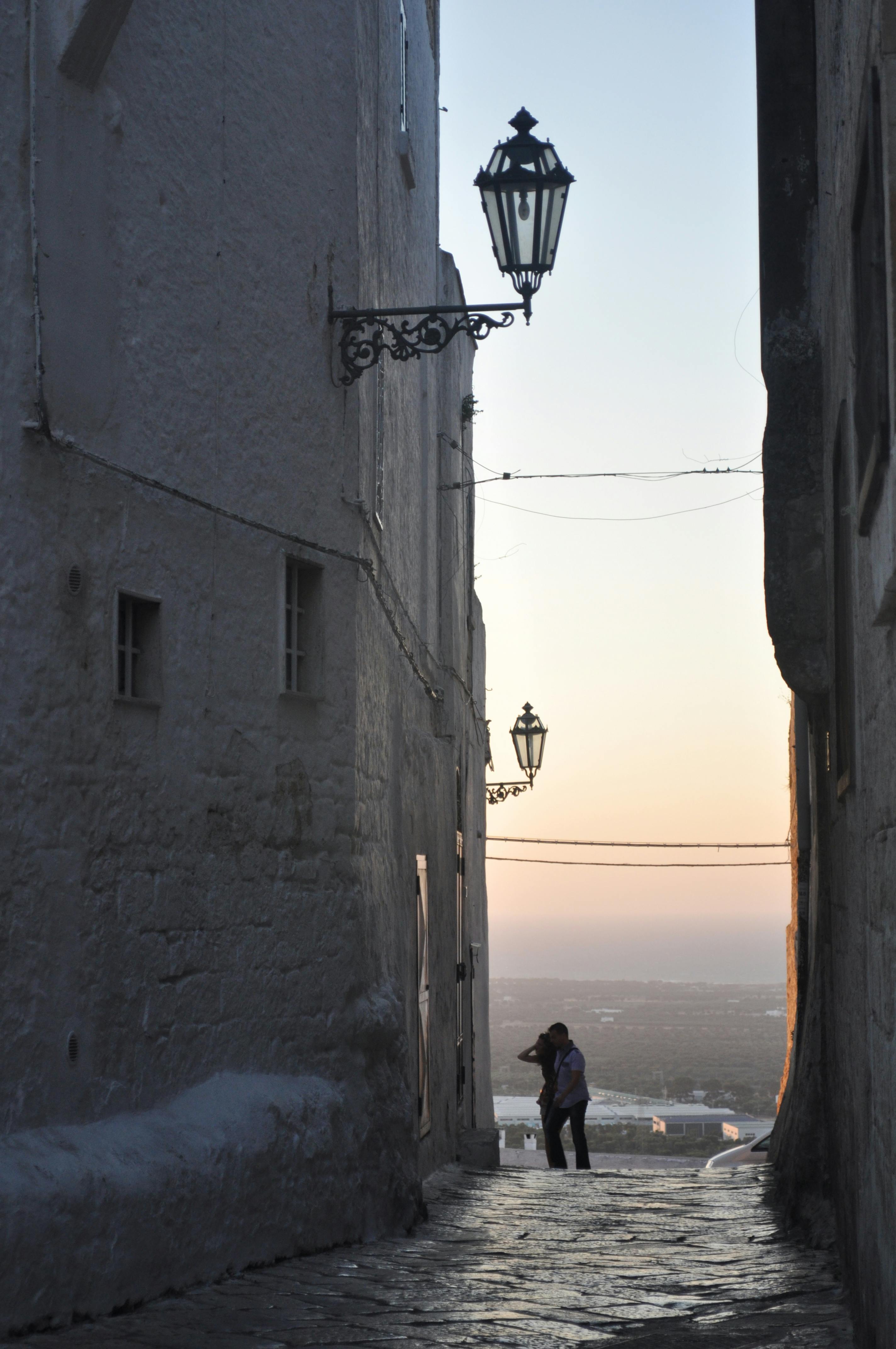 Between white houses a view of the beautiful flat landscape with vineyards and in the distance the sea during sunset in Puglia.