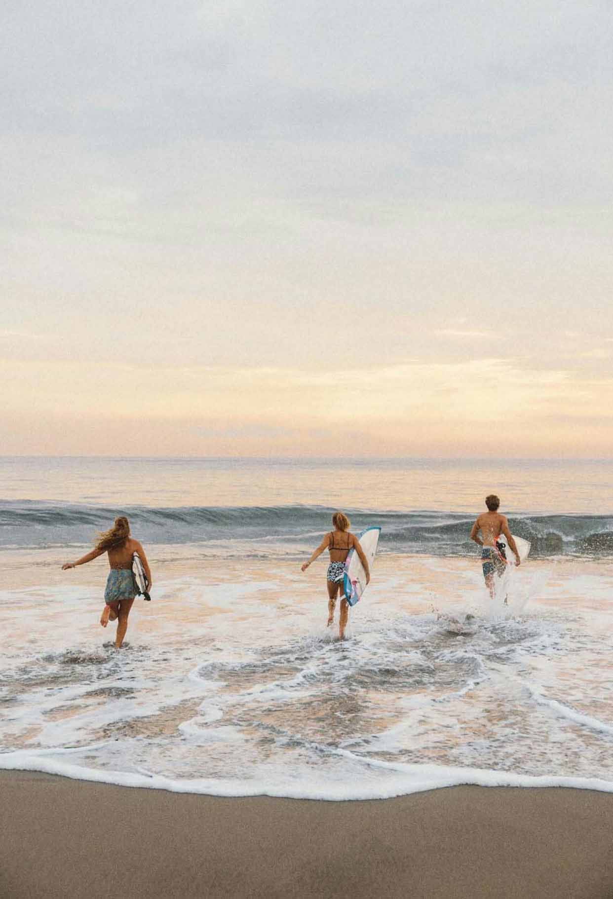 people entring the sea with surfboards