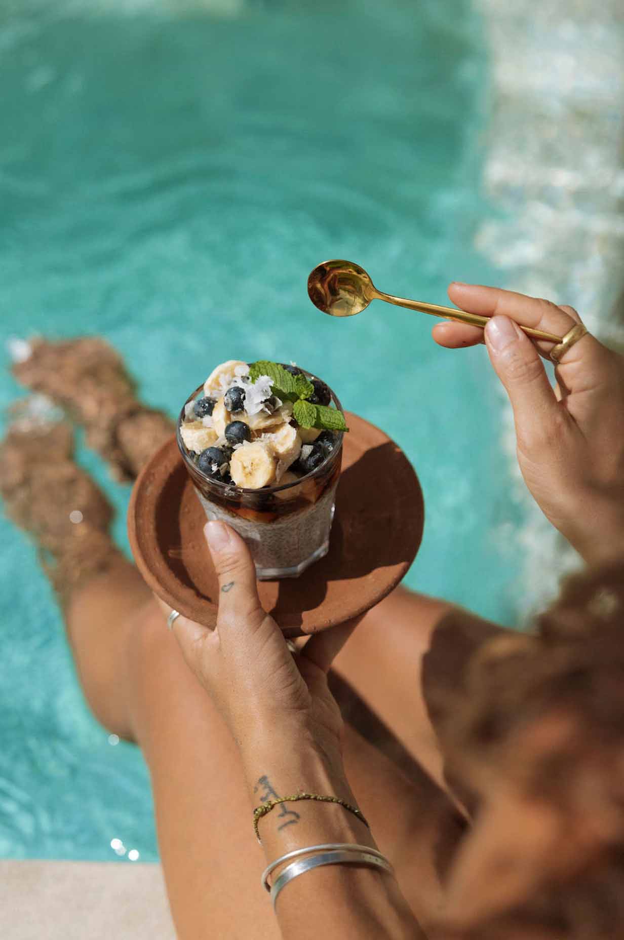a girl eating icecream next to the pool