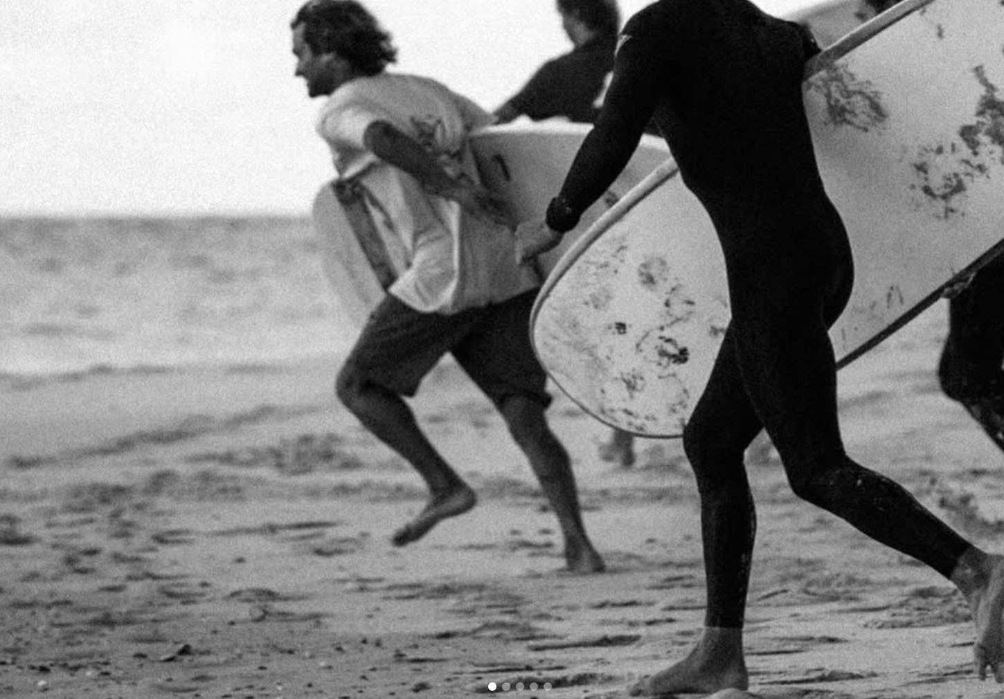 guys runing on the beach with a surfboard
