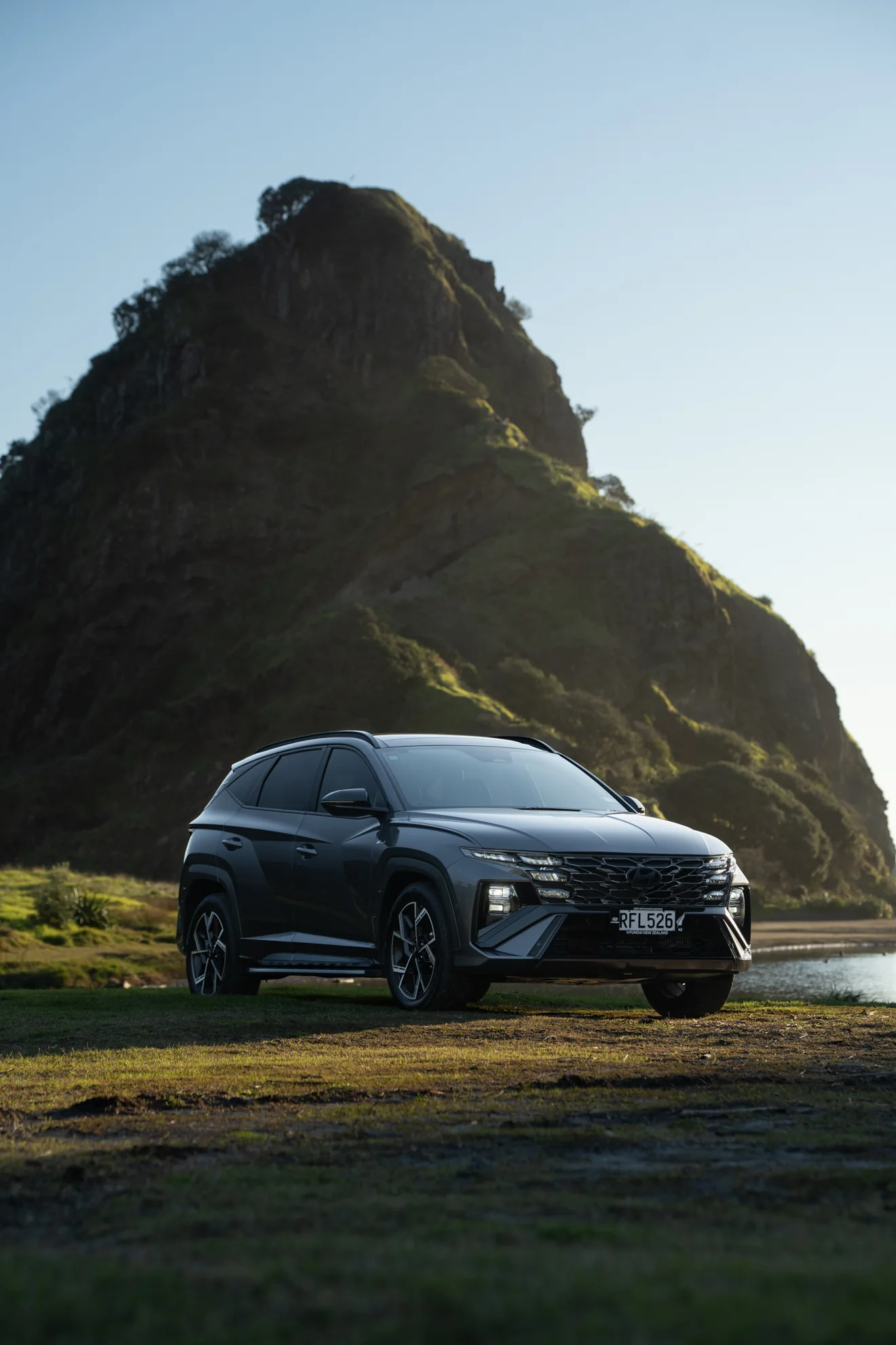 Dark Hyundai Tucson below Lion Rock at Piha