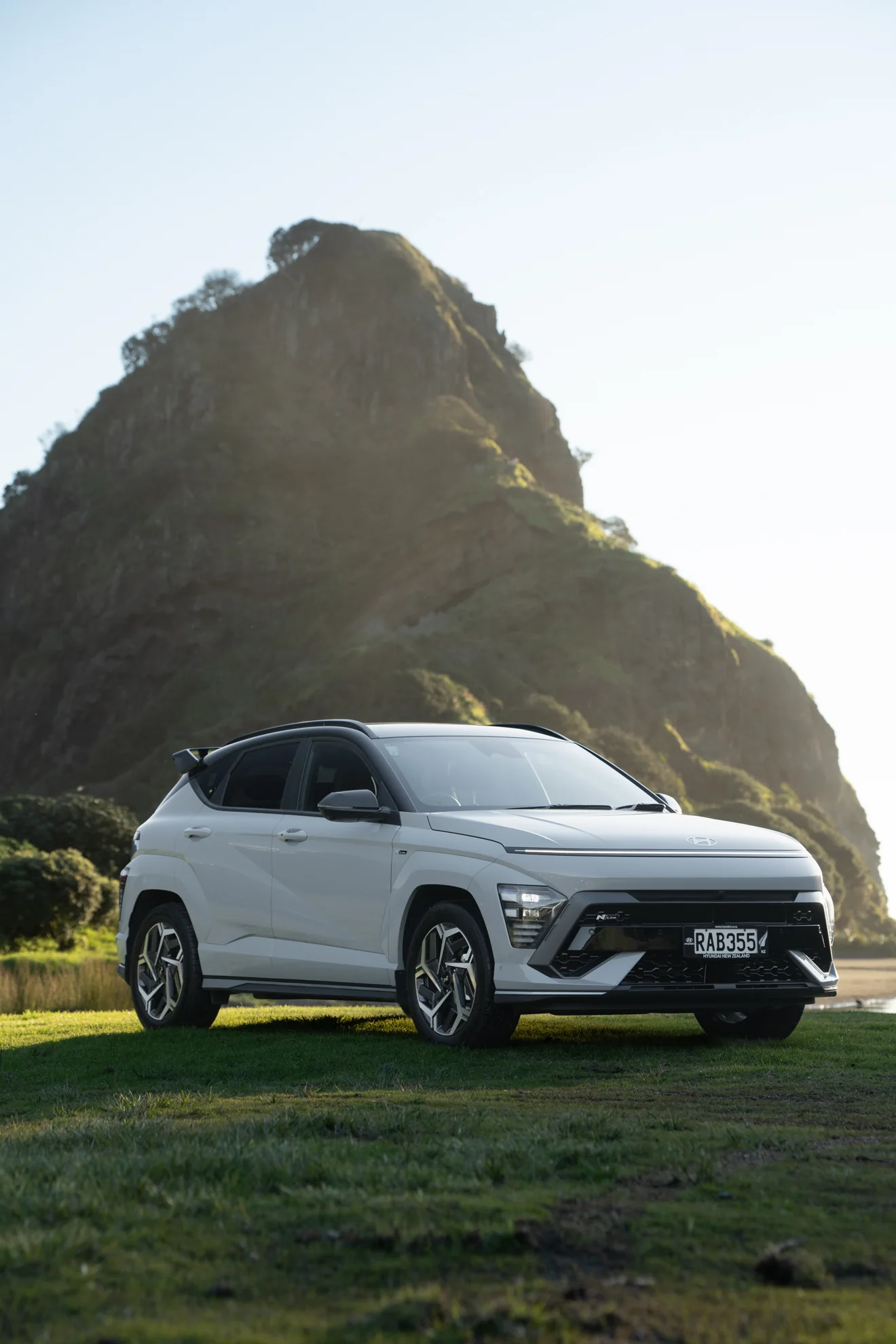 White Hyundai Kona below Lion Rock at Piha