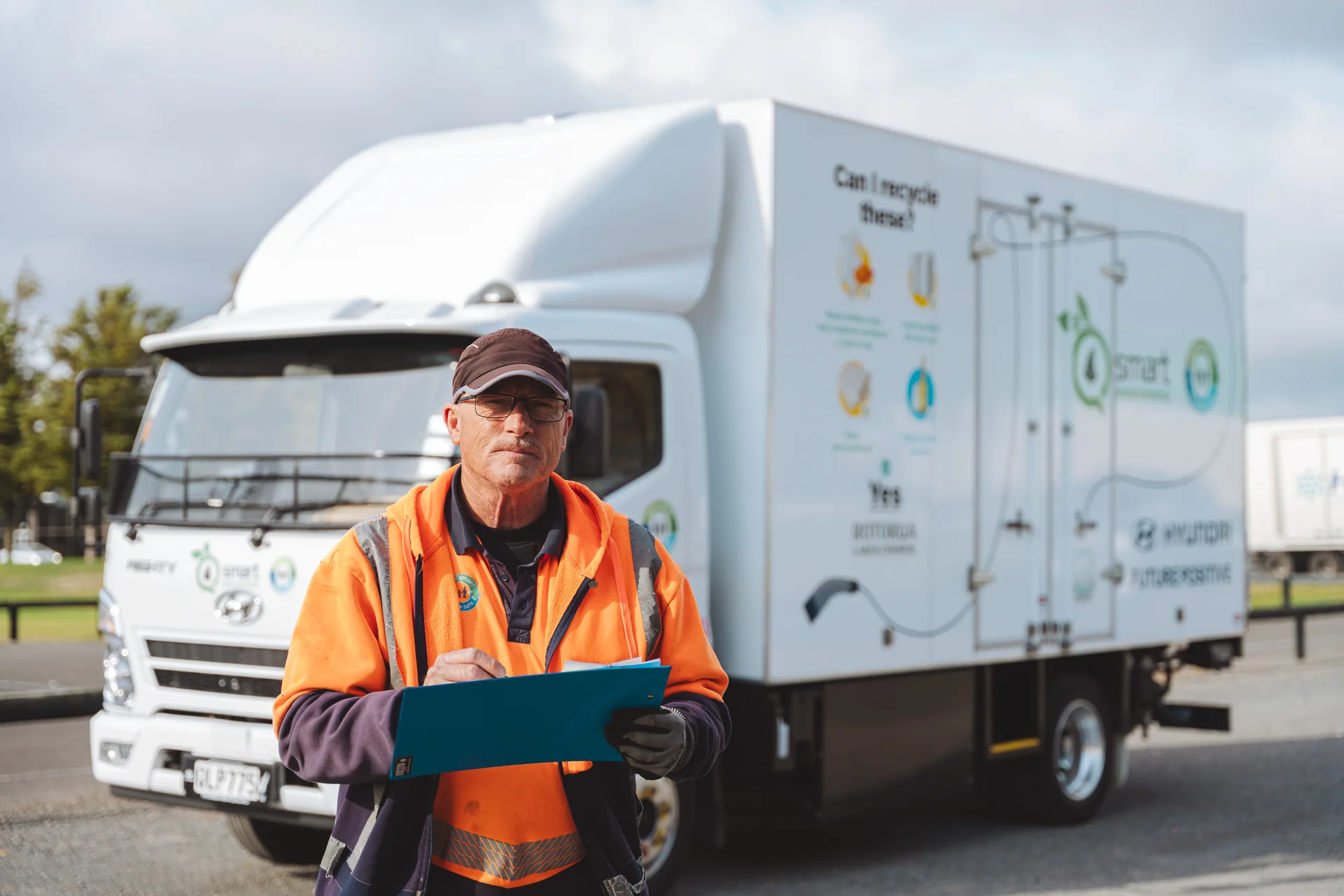 Driver in hi-vis holding a clipboard in front of a Hyundai truck