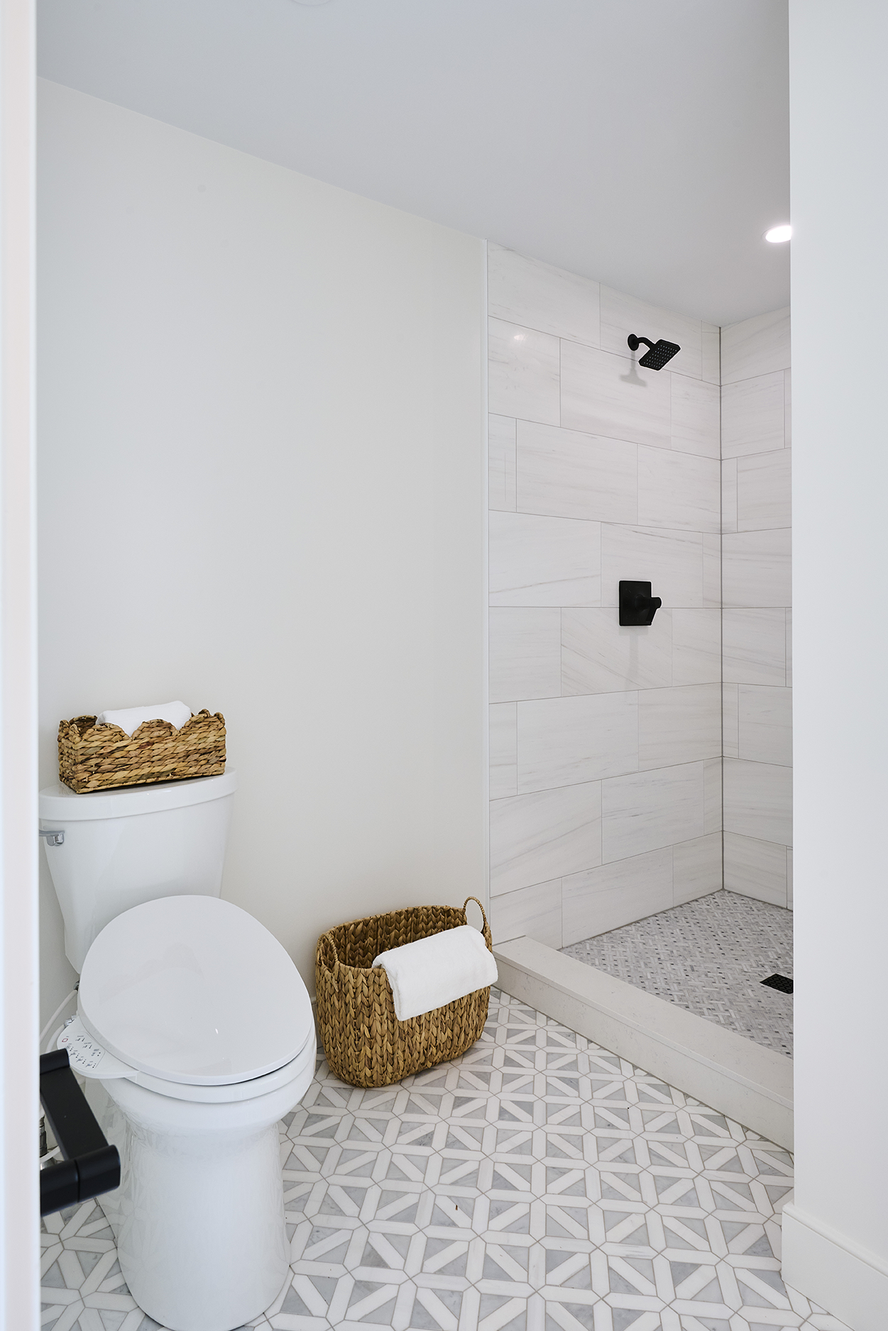 Oversized Bianco Dolomite tiles create a serene backdrop in this walk-in shower, their horizontal installation emphasizing the room's clean lines