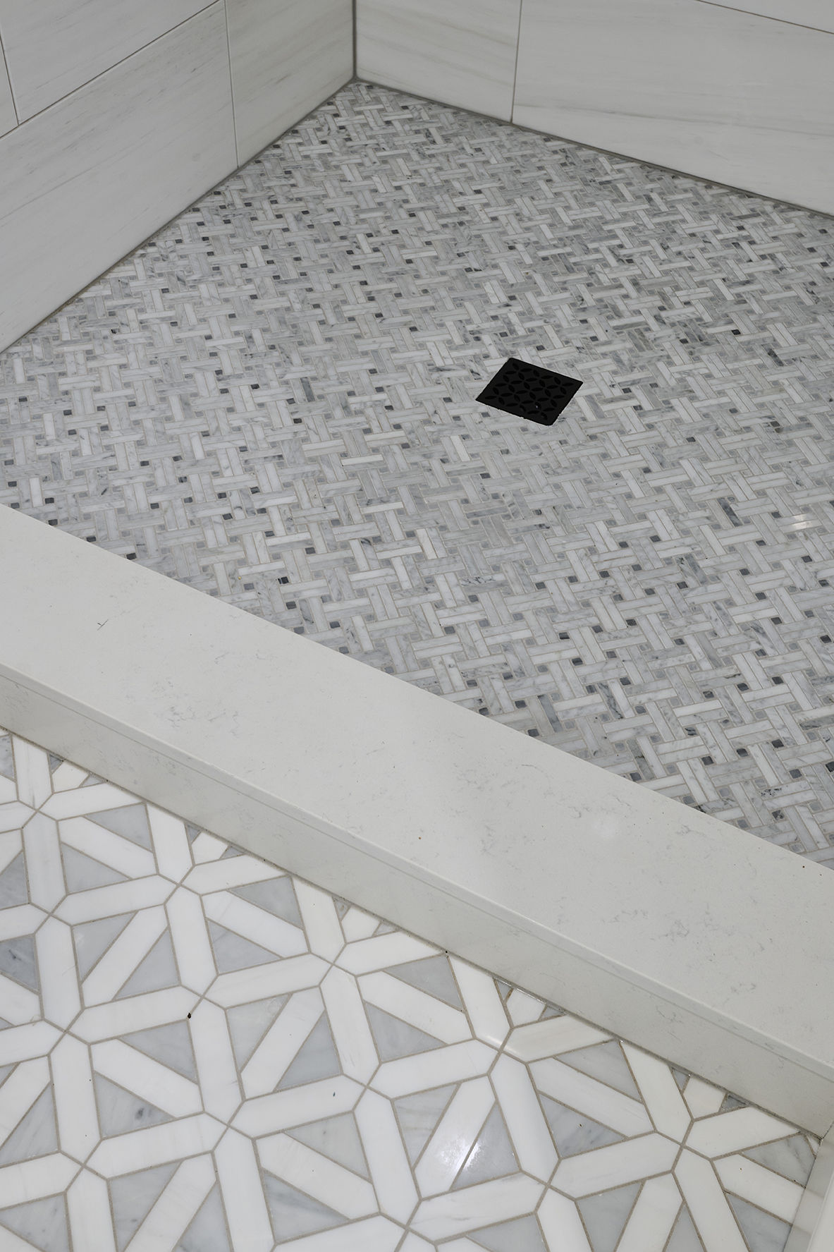 Carrara white basketweave mosaic defines the shower floor, while Bianco Dolomite Geometrica tiles extend throughout the bath
