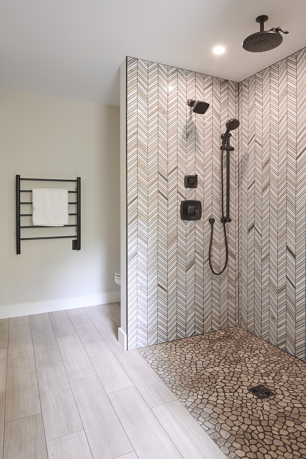 Tumbled white oak pebble flooring adds organic texture underfoot, and light wood plank flooring flows throughout