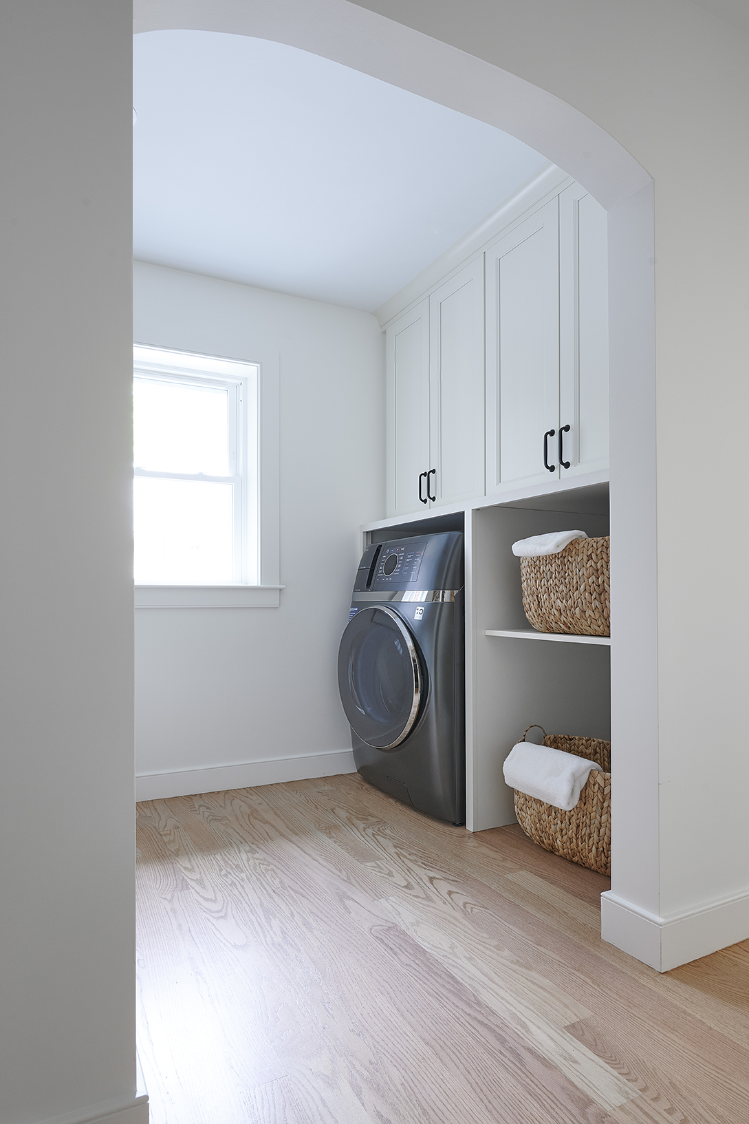 White shaker cabinets provide closed storage above, while open cubbies below keep everyday essentials within easy reach