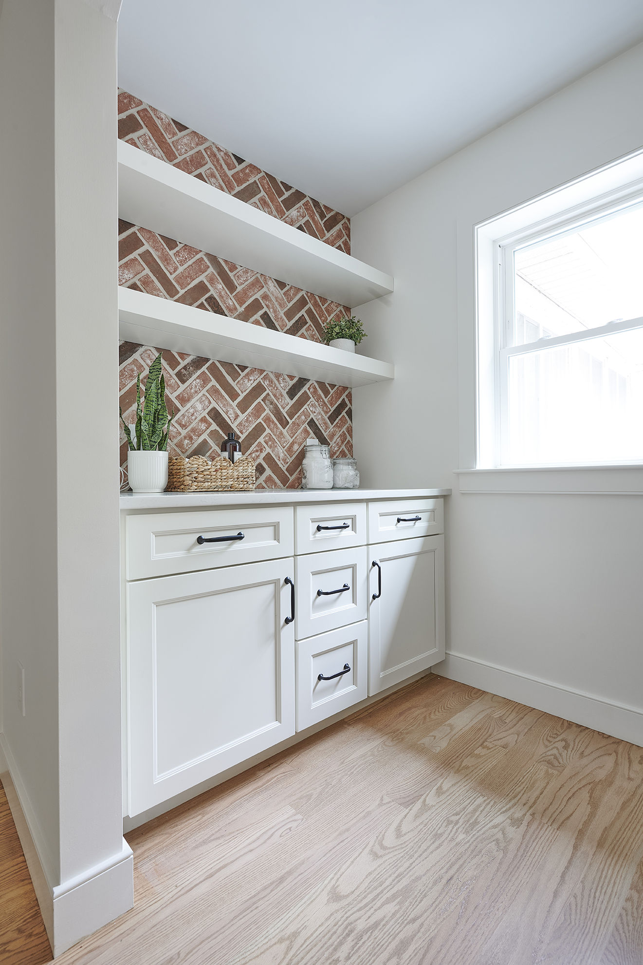 A herringbone brick accent wall brings warmth and texture to this custom laundry station