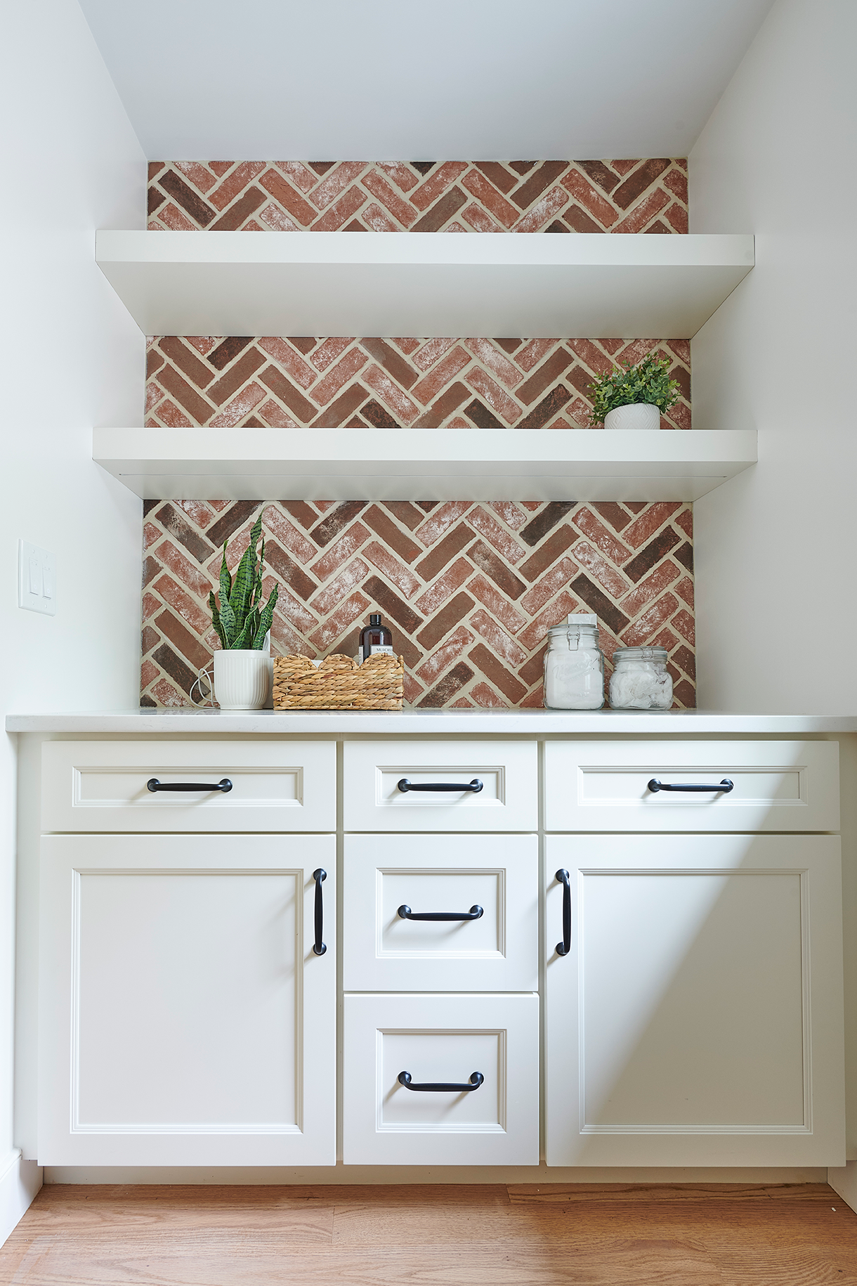 White floating shelves create display opportunities above a practical workspace, while shaker cabinets below offer ample concealed storage