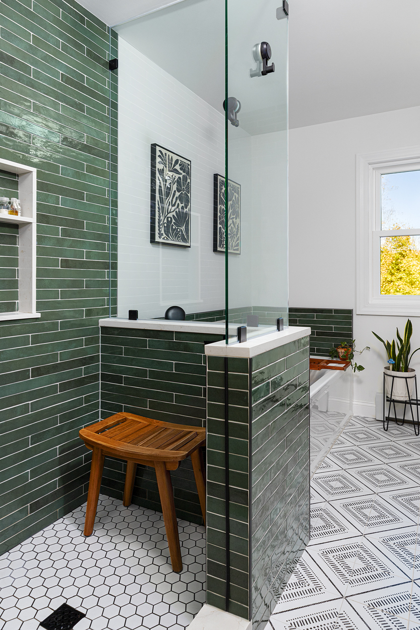  A mossy green tile surround envelops the shower and tub in quiet depth, anchored by dark grout and crisp white walls.