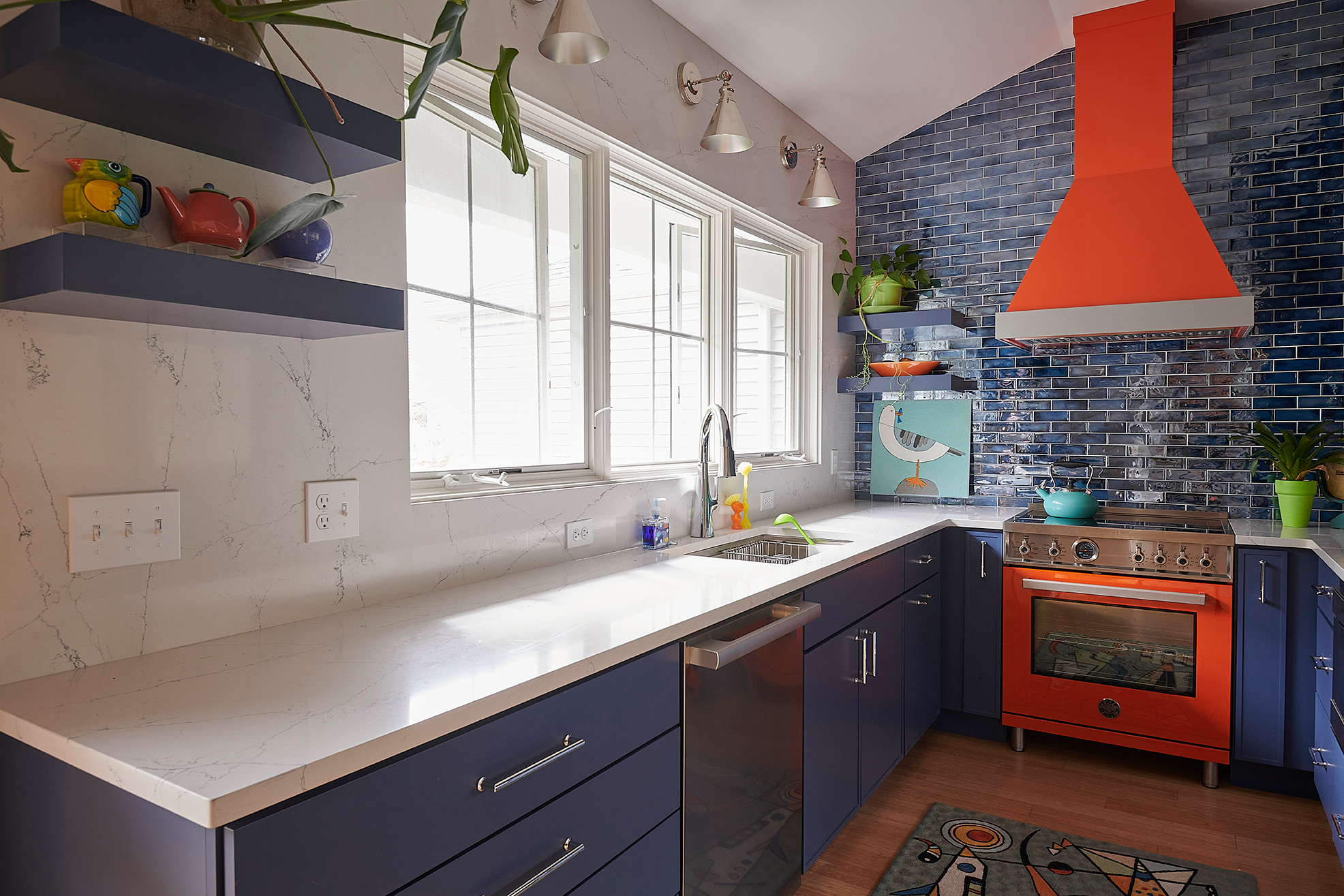 The fusion of coastal sophistication and industrial edge is brought to life with sleek sconces above the sink and statement blue floating shelves that elevate the space with bold, effortless style.