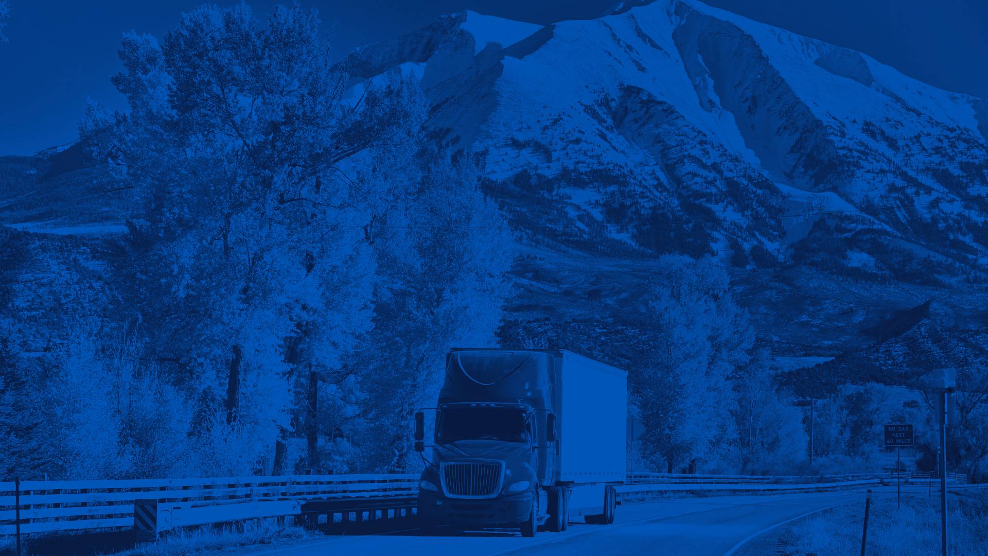 Red Semi Truck on a Highway with Snowy Mountains in the Background