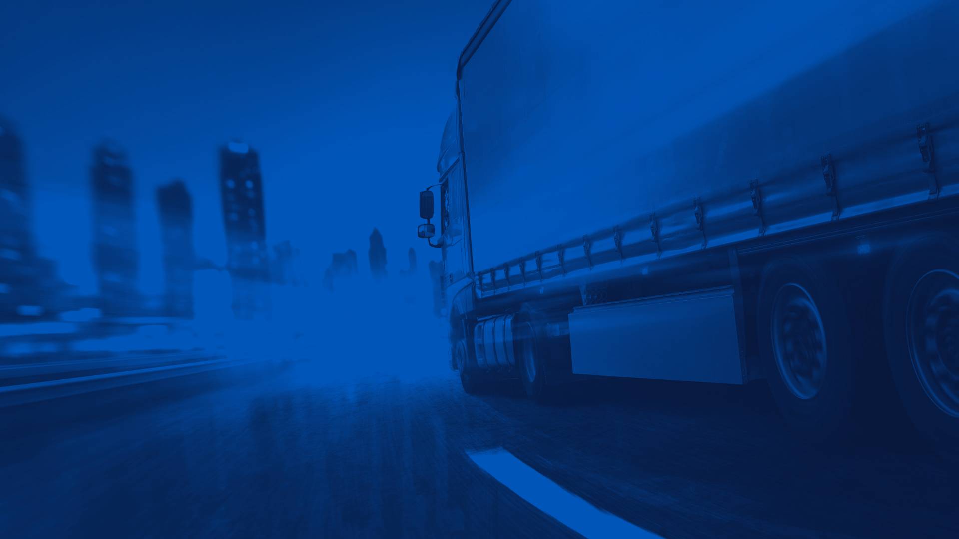 Semi Truck Driving on a Freeway with City in the Background