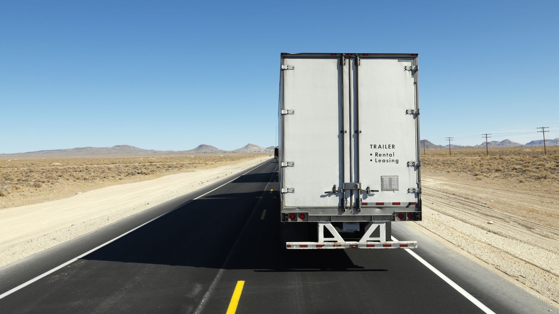 Rear of White Semi Trailer on a Desert Highway