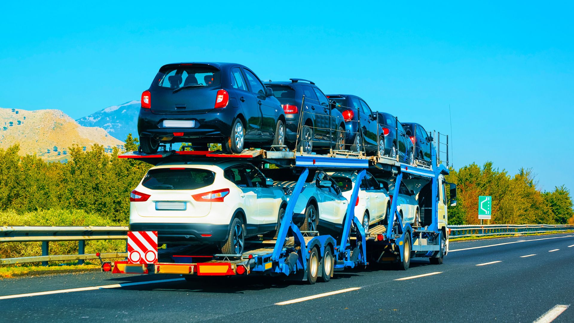 Semi Truck Hauling a Trailer of New Cars on a Highway
