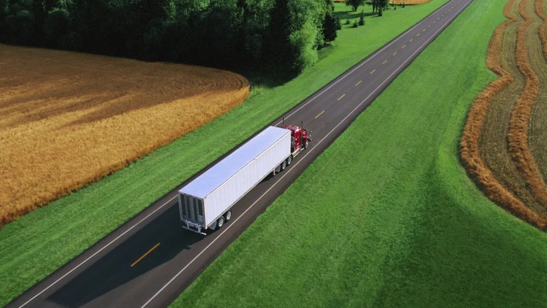 Overhead View of Semi Truck Driving Past Green Fields
