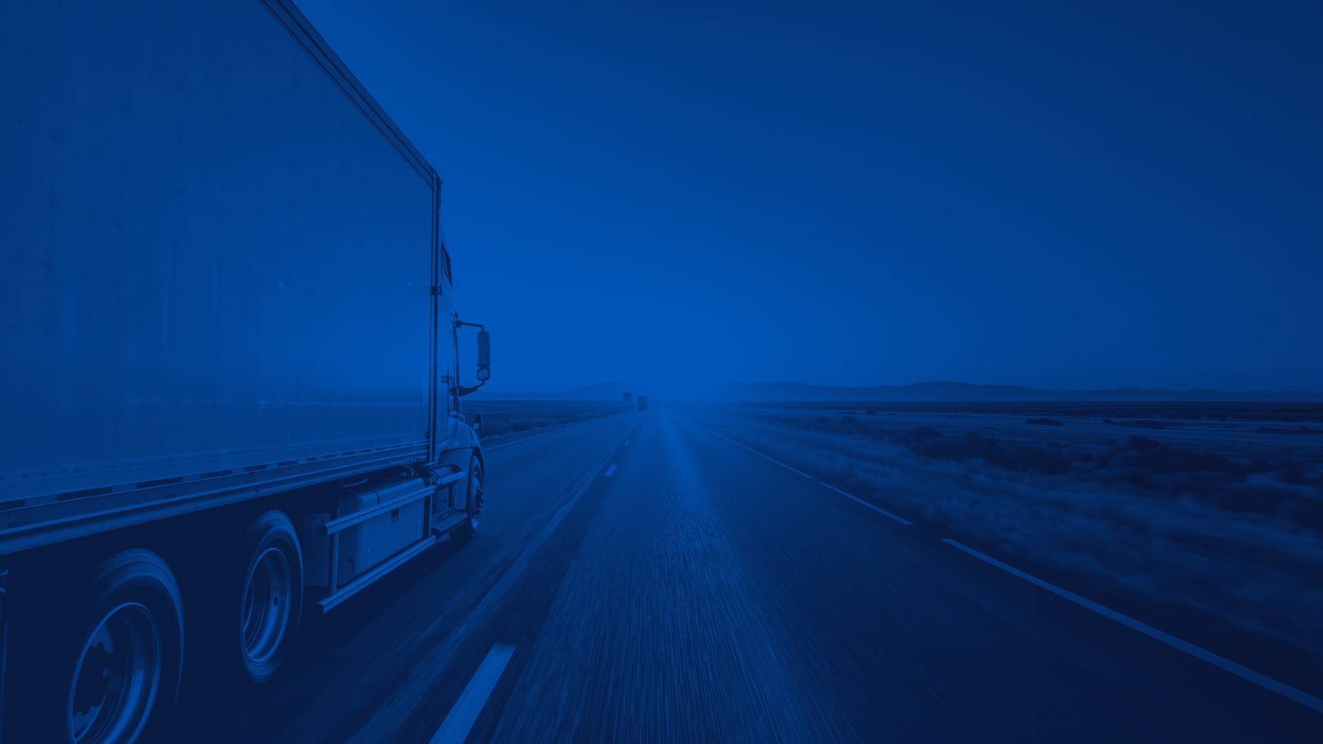 Semi Truck Driving on Desert Highway at Sunset