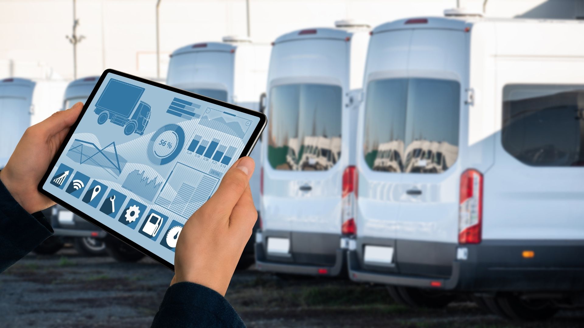 Person Looking at Fleet Data on a Tablet in Front of a Line of White Fleet Vehicles