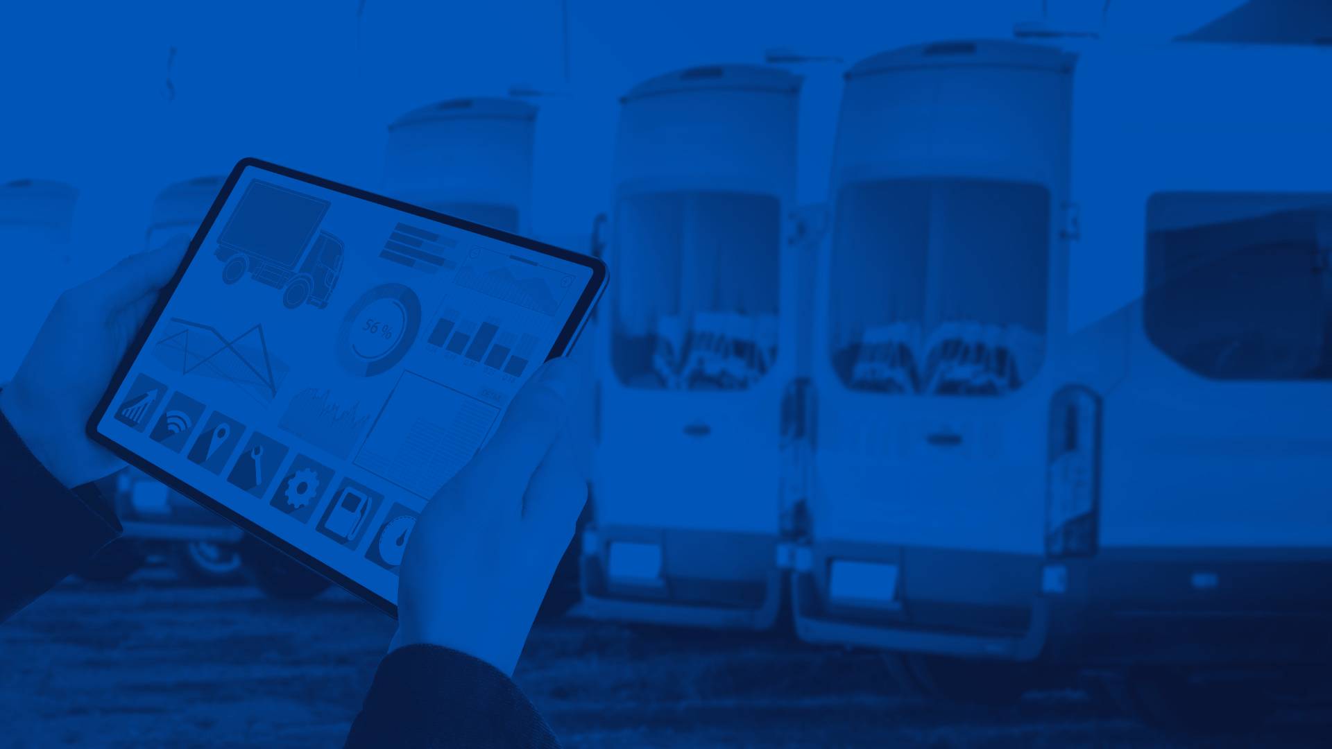 Person Looking at Fleet Data on a Tablet in Front of a Line of White Fleet Vehicles