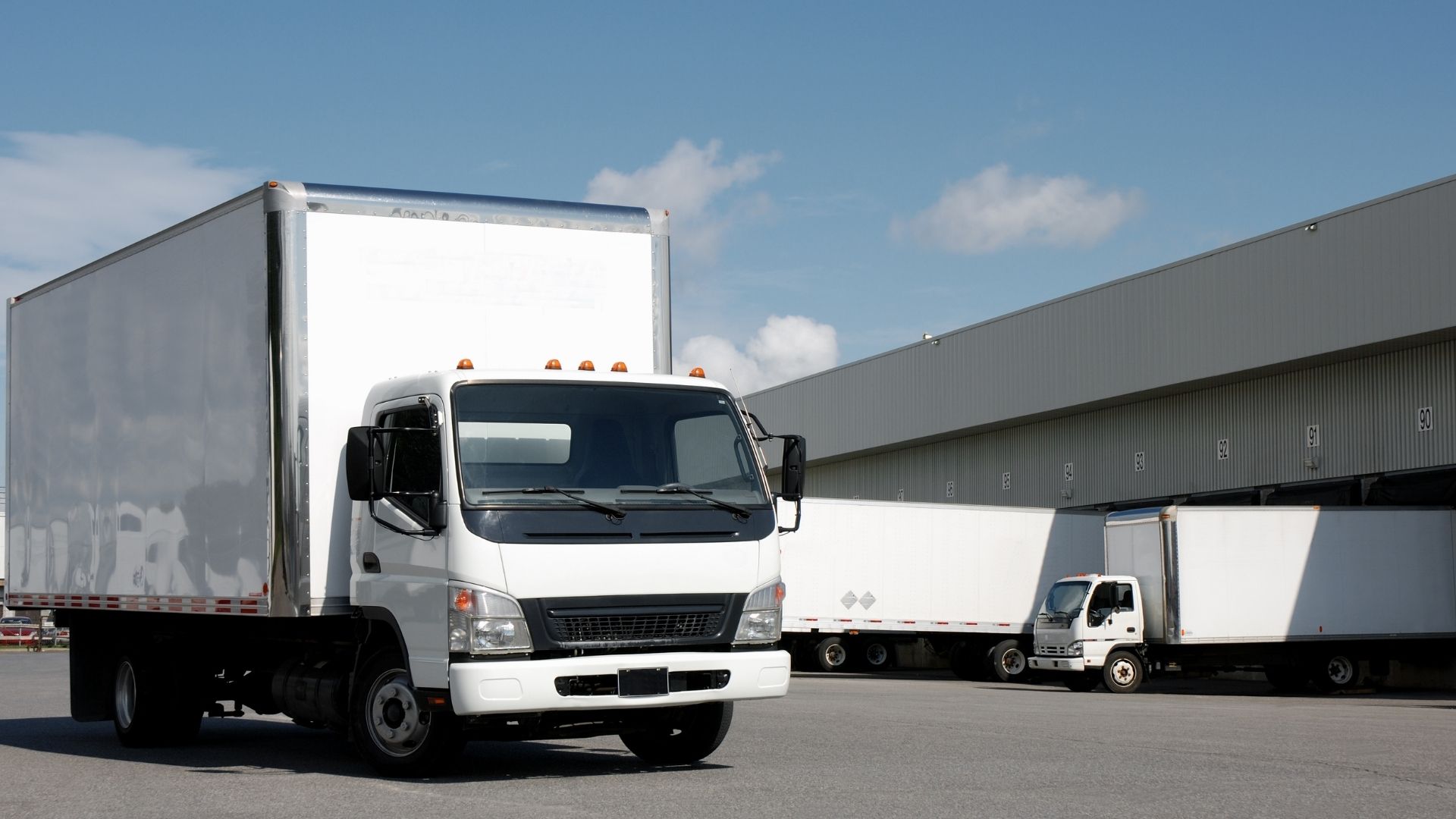 White Box Trucks Next to a Building and Loading Dock
