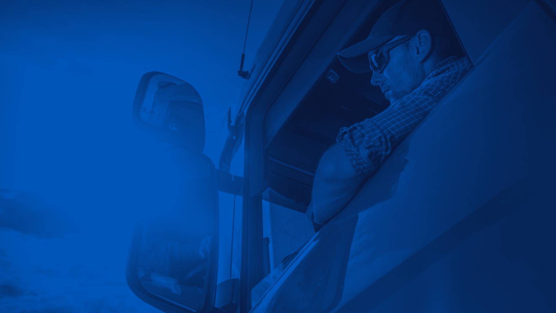 Man Behind the Wheel of Red Semi Truck with Sun Shining