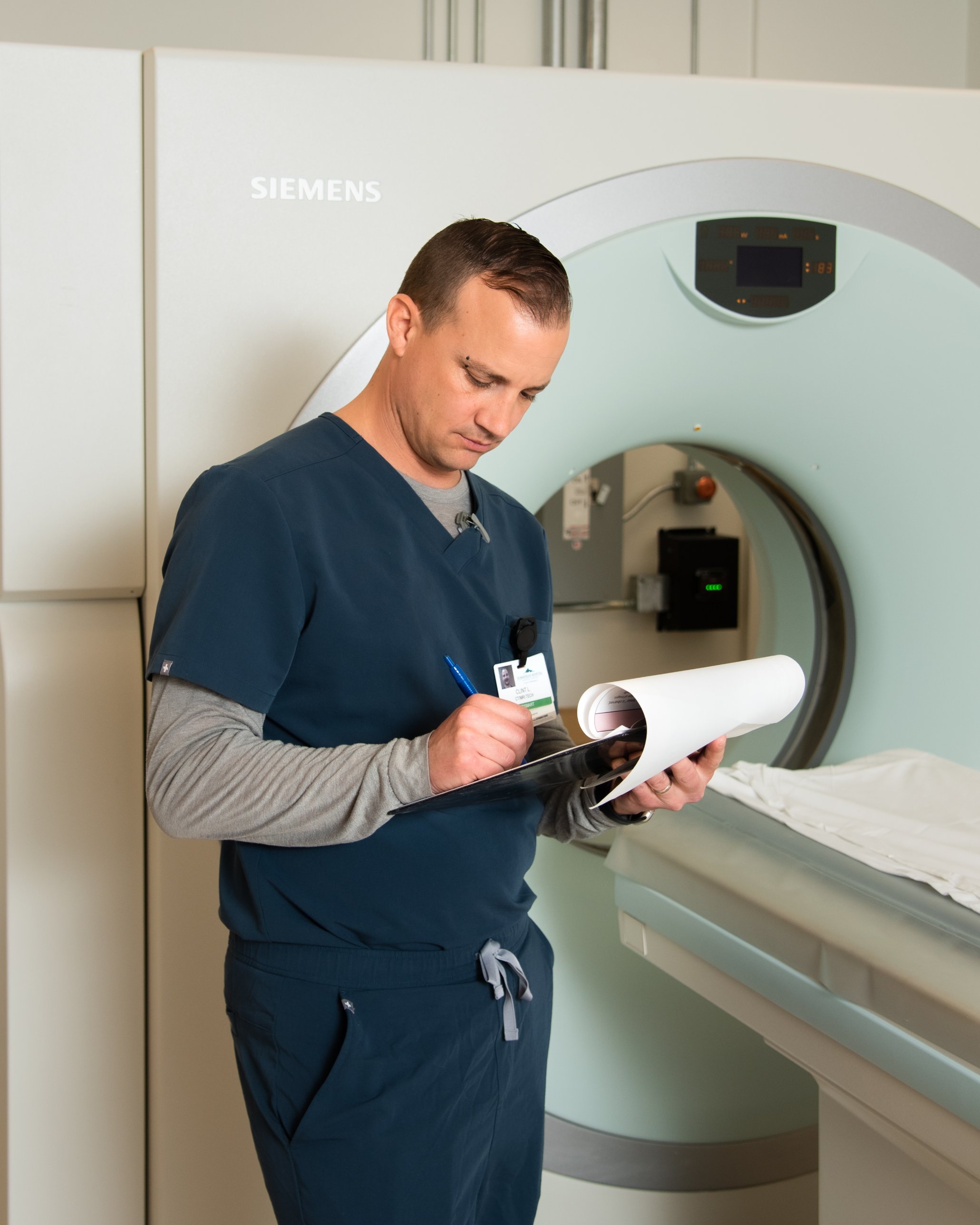 MedSmart CT technologist reviewing paperwork beside a CT scanner