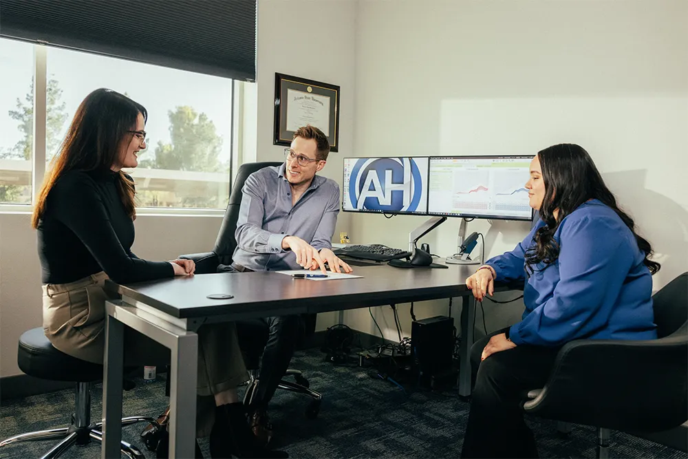 Dr Clff, Kelsey and Leslie sittitng at a desk, discussing hearing test results