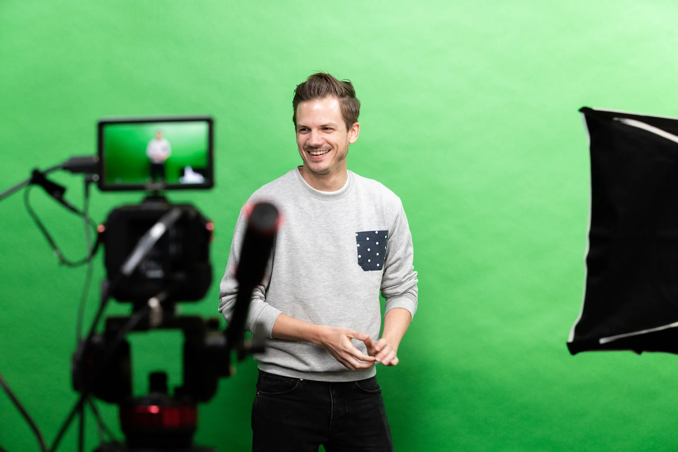 Une personne sourit devant un fond vert