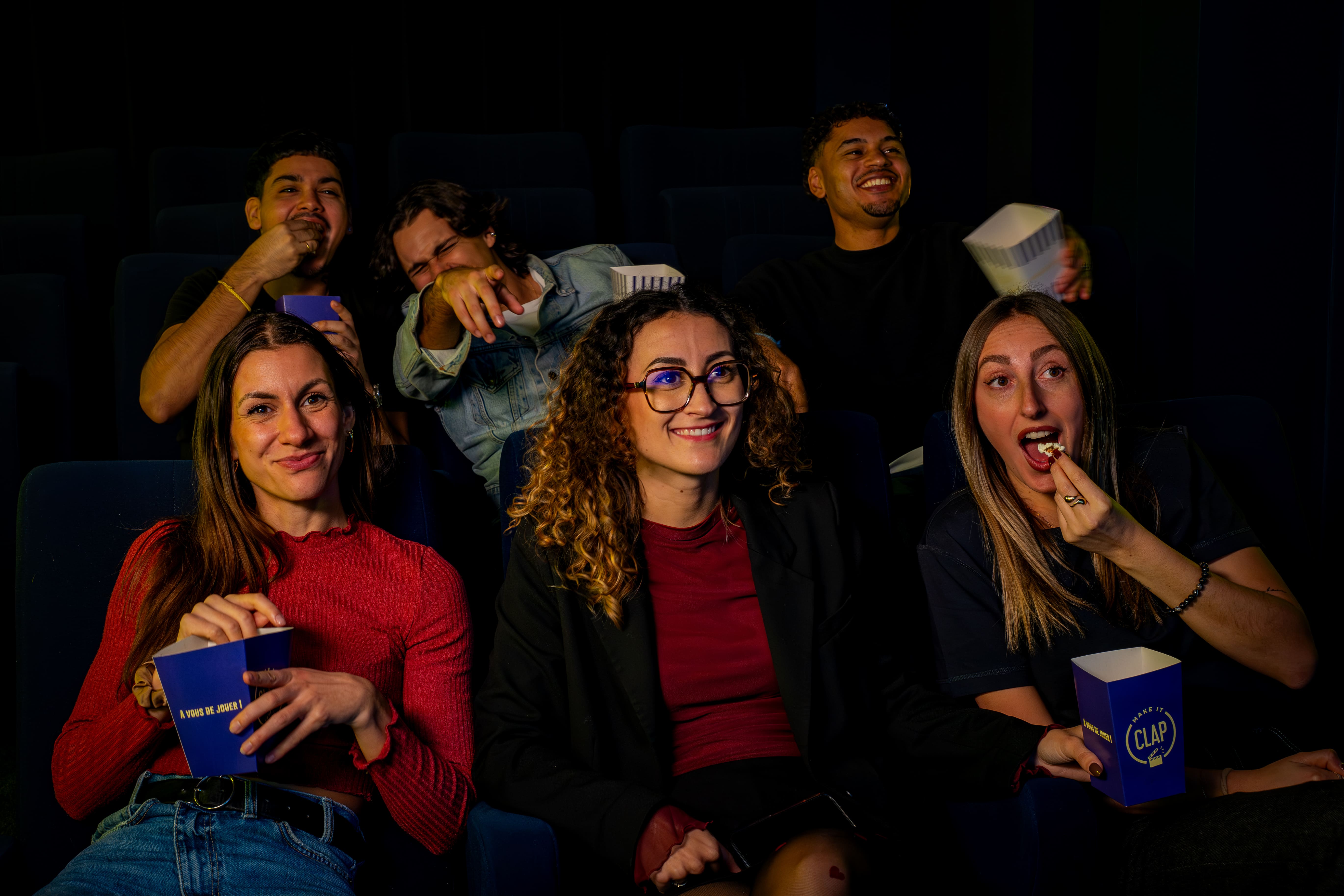 A group of friend watching their movie in a movie theater while eating popcorn