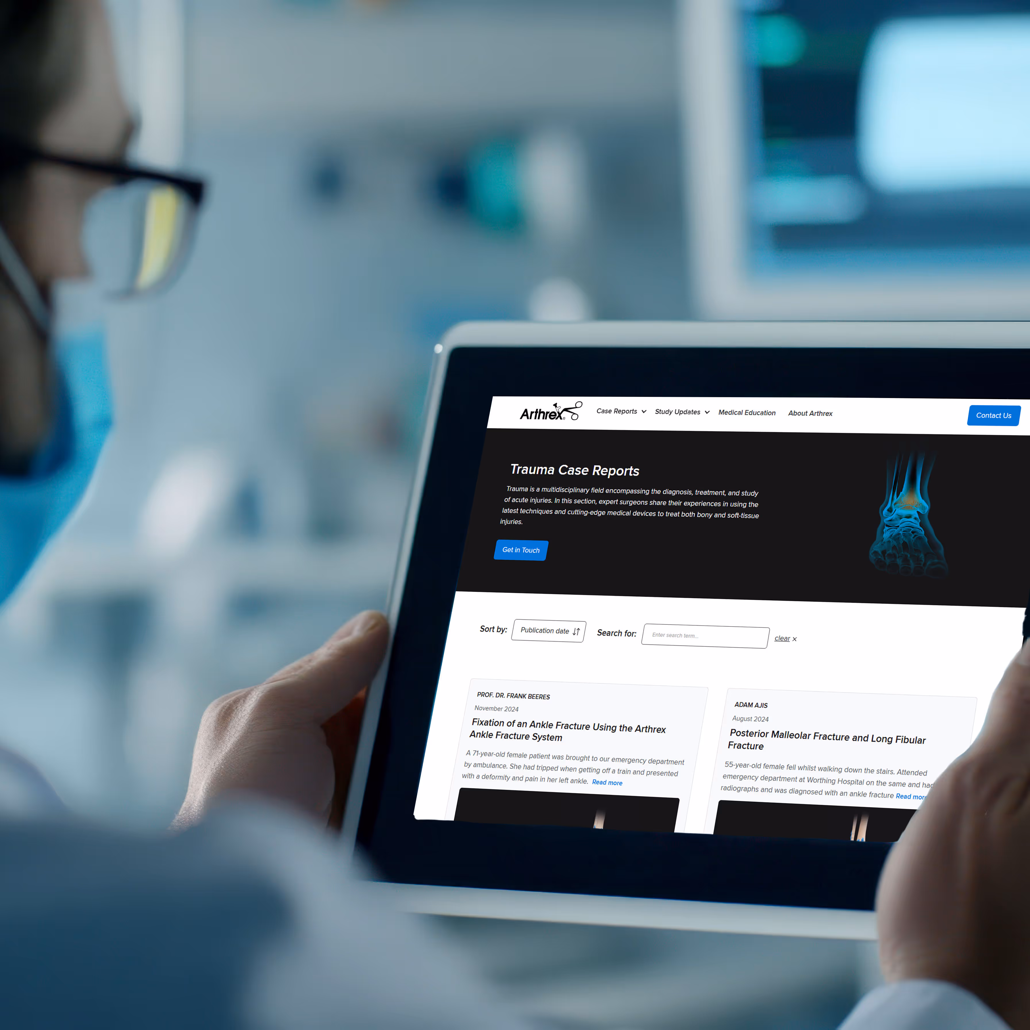 A surgeon wearing a medical mask reads the Trauma Case Reports website on a tablet.