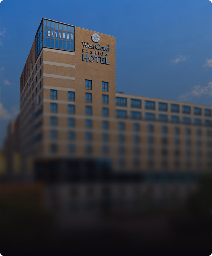 Large multi-story beige building under a blue sky with signage reading 'WestCord Fashion Hotel' and a section labeled 'Skybar'.