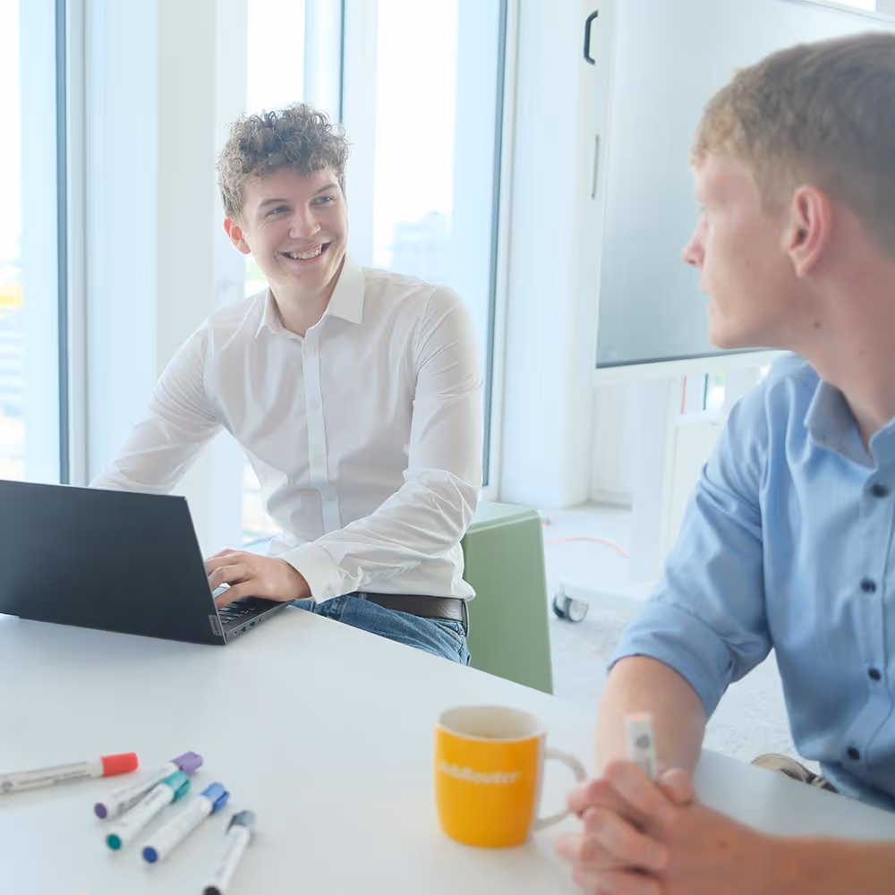 Zwei Mitarbeiter sitzen im Meetingraum und diskutieren das weitere Vorgehen.