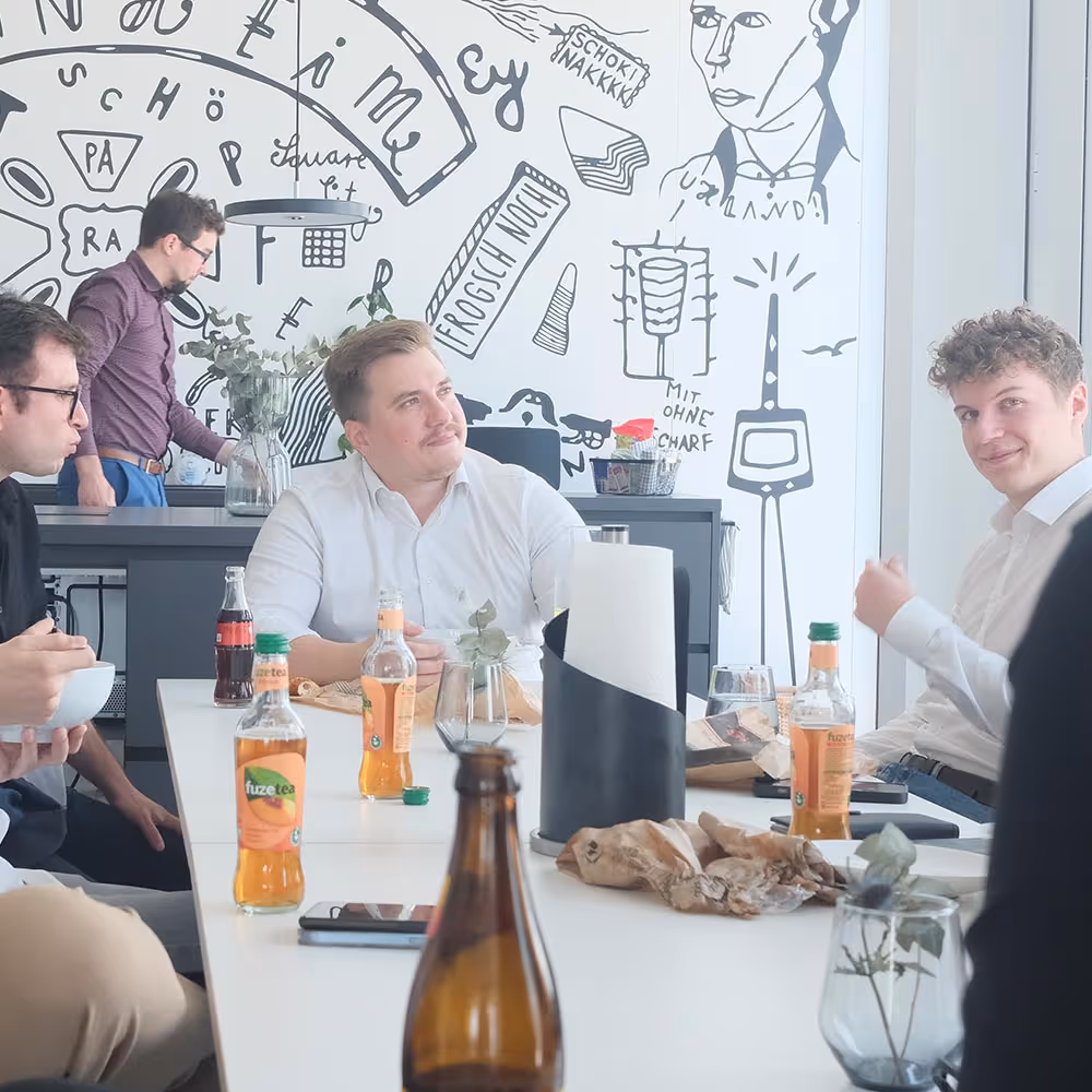 Die Mitarbeiter der Wertschöpfer IT GmbH sitzen zusammen beim Mittagessen im Workcafe.