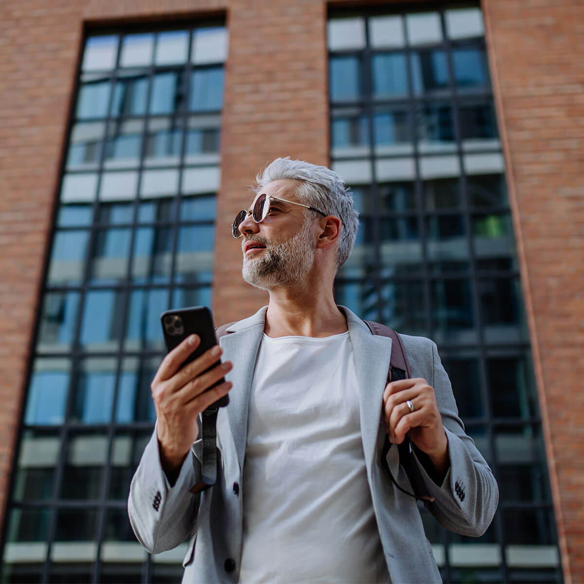 Man står utanför kontorsbyggnad med en mobiltelefon