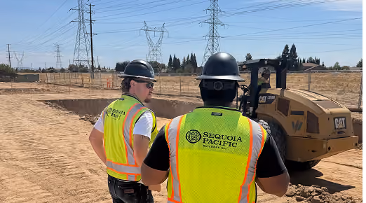 Two Sequoia Pacific Builders employees seen from behind, standing on the jobsite.