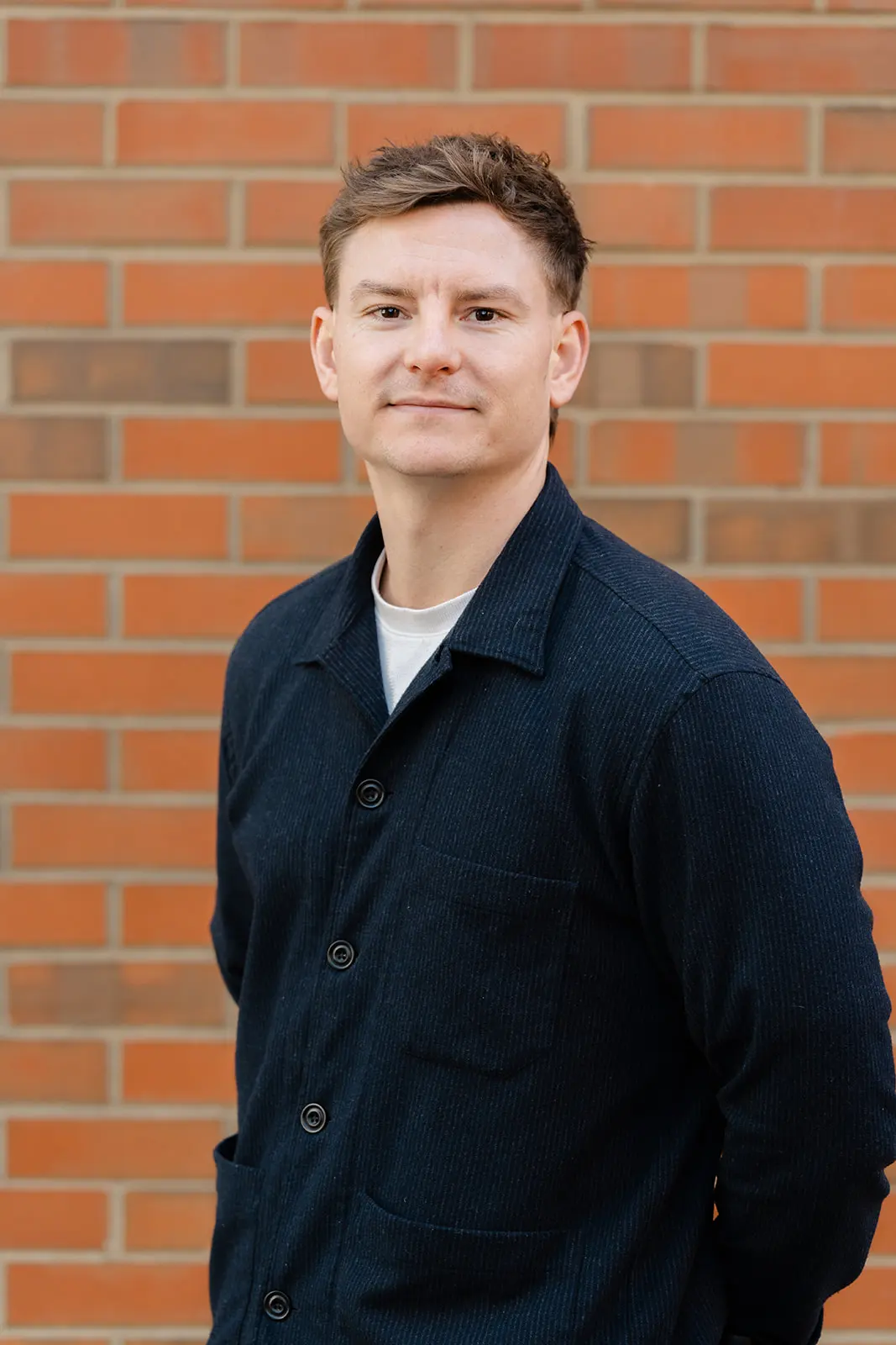 Headshot of a man against a brick wall