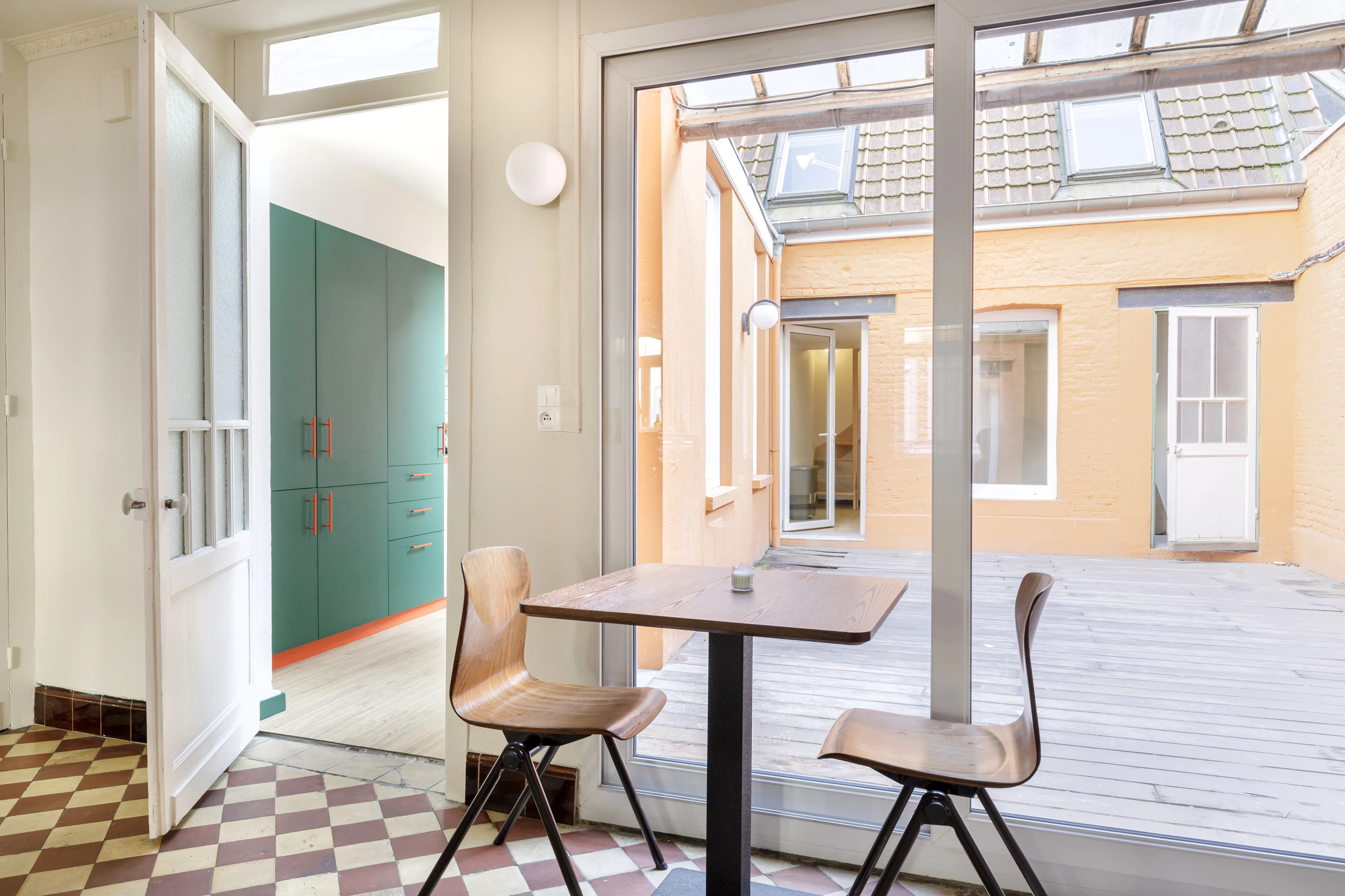 Coin repas d’une maison Roof à Lille, ouvert sur une cour intérieure avec terrasse en bois