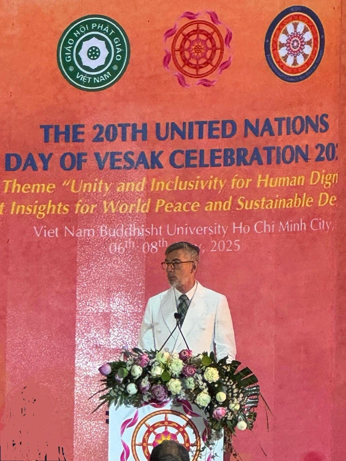 A person standing at a podium with a bouquet of flowersAI-generated content may be incorrect.