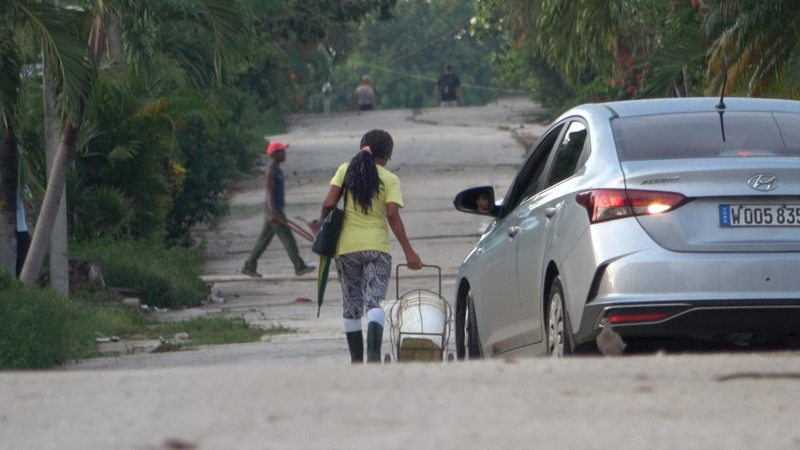 A person pulling a cart next to a silver carAI-generated content may be incorrect.