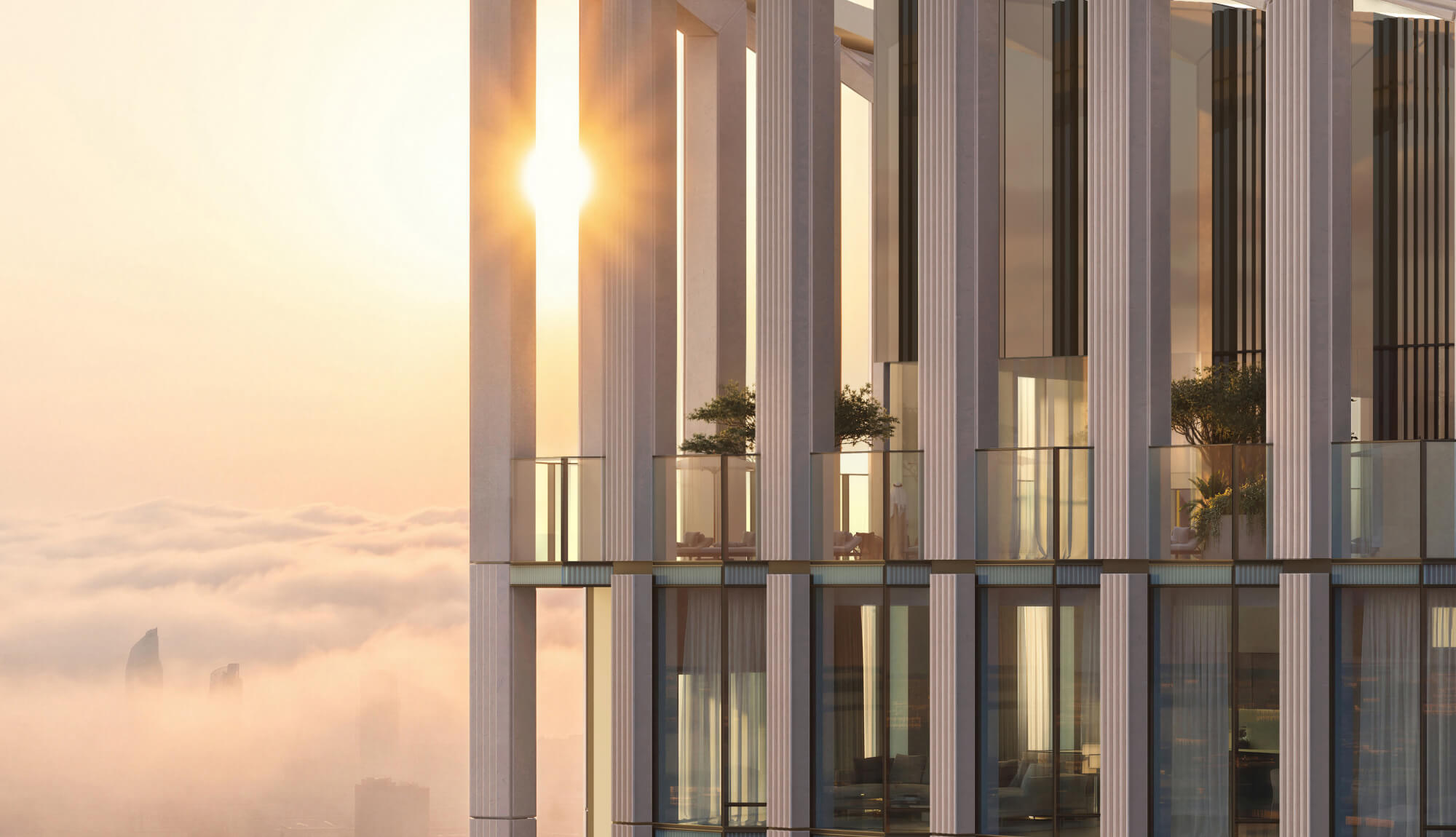 Modern high-rise building with white columns overlooking city shrouded in fog at sunset.