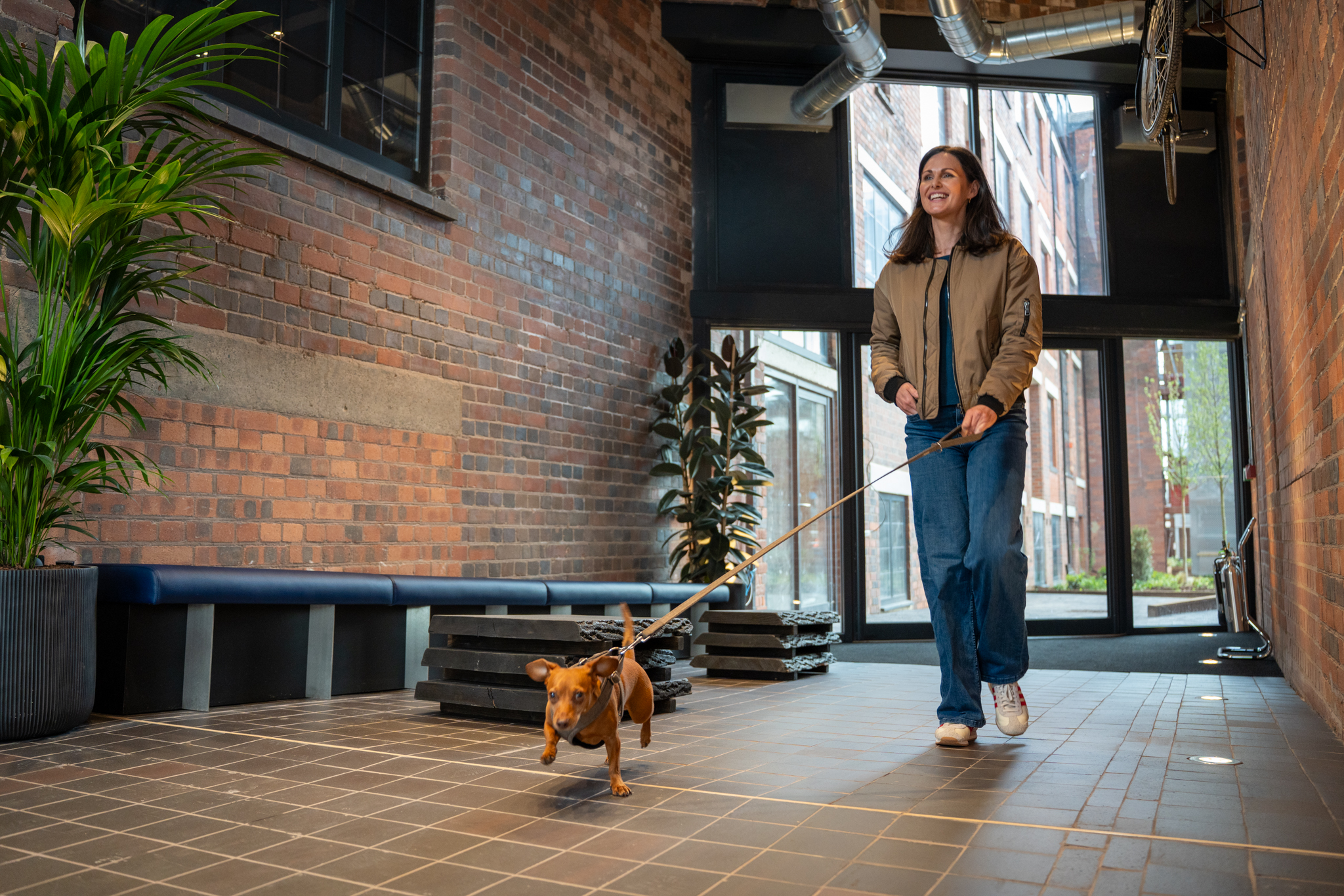 A resident walking her dog through the entrance of The Sunbeam in Wolverhampton, highlighting the development’s pet friendly design and welcoming atmosphere.