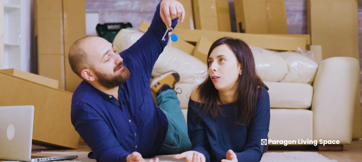 A man and woman relax on the floor surrounded by boxes, illustrating the theme of renting versus buying in the UK.