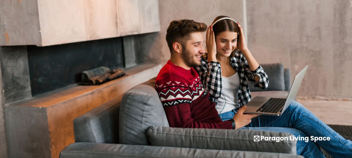 A couple sits on a stylish couch in a luxury lounge, engaged with a laptop in a cozy apartment setting.