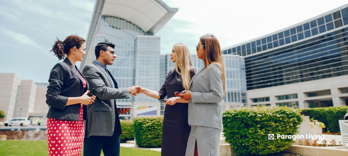 Business professionals shaking hands in front of a modern building, symbolizing collaboration in sustainable luxury development.