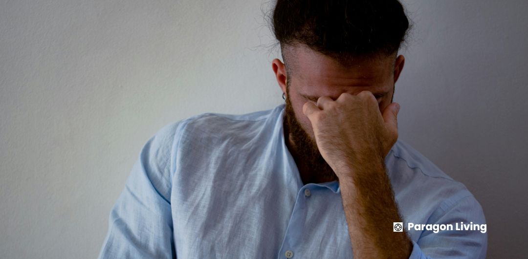 A man holds his head in his hands, expressing frustration over common delays in the UK renting process.