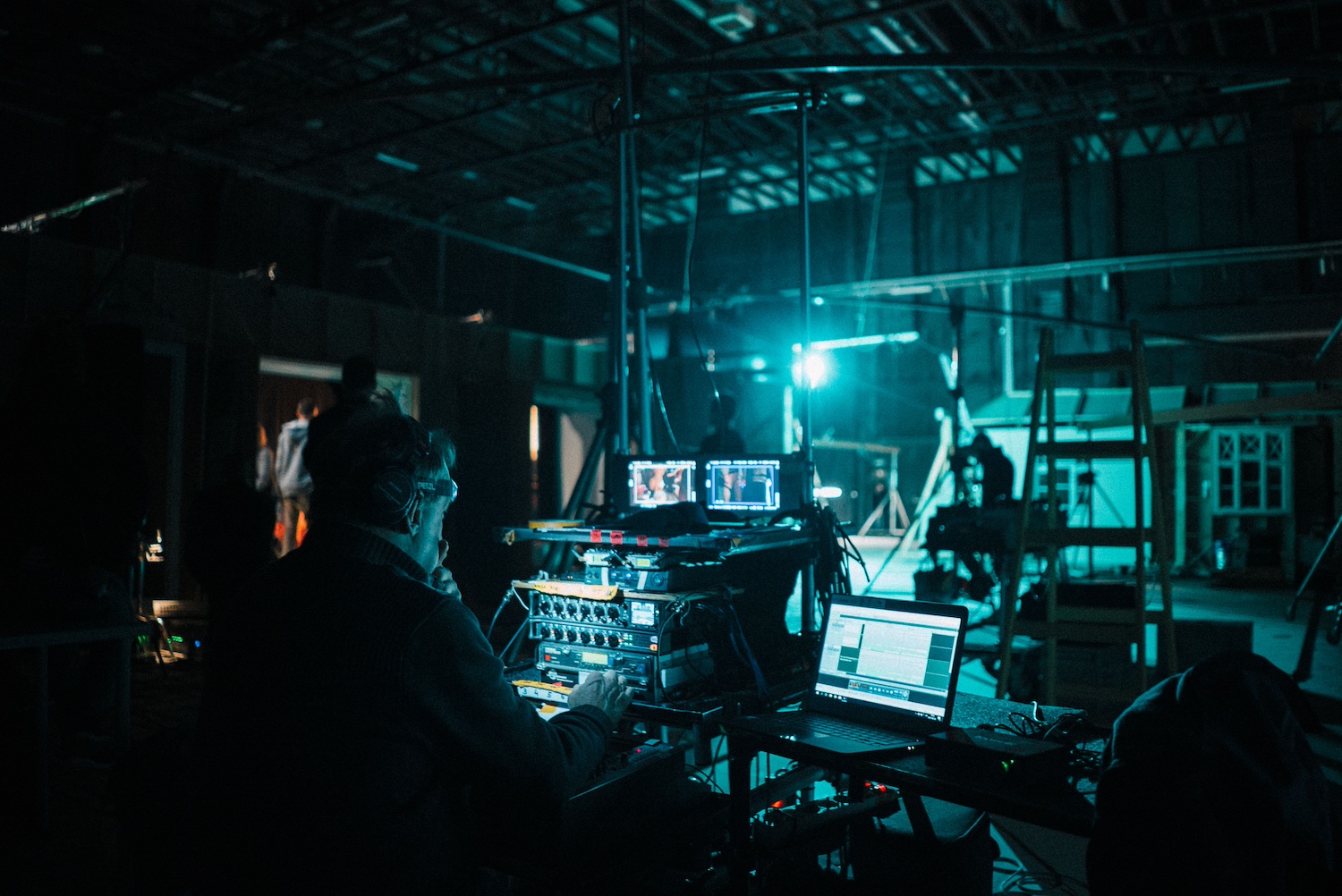 Un plateau de tournage en lumière contrastée avec des personnes qui travaillent sur un film