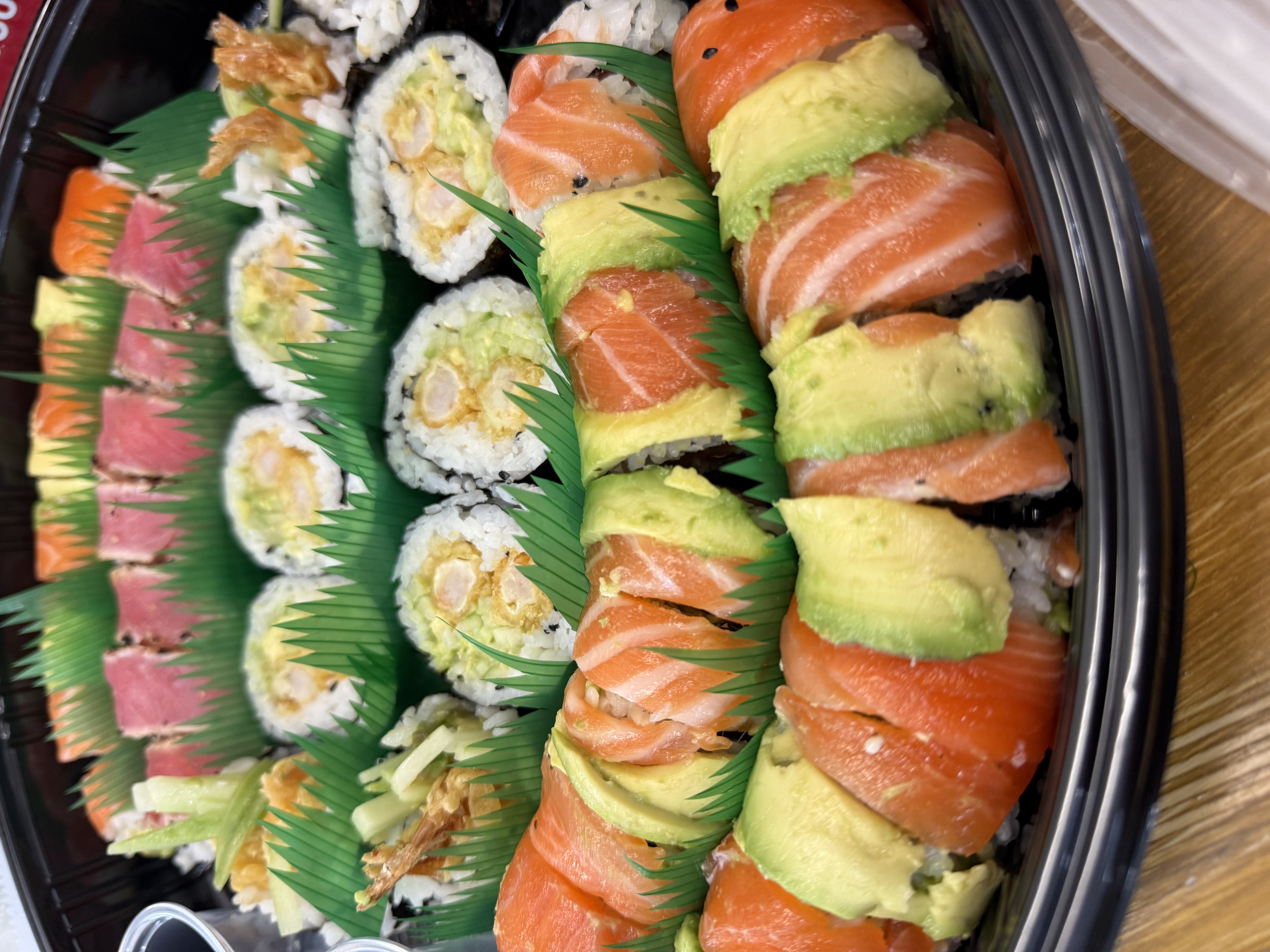 A platter with salmon sushi, avocado, shrimp tempura and other colorful rolls.
