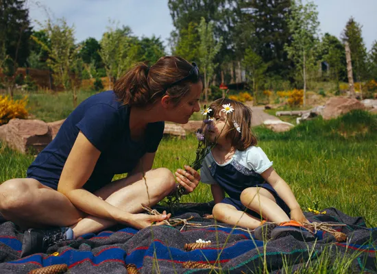 Une mère et sa fille sentant des fleurs à l'extérieur