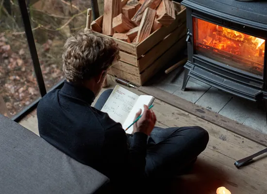 Man reading a book in front of the woodstove