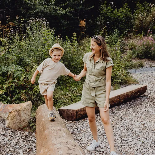 Une maman aidant son fils à franchir un tree trunk tombé tree trunk les vacances avec ses enfants dans les Ardennes belges.